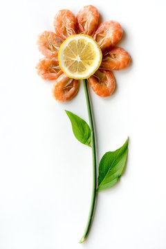 Isolated flower from boiled shrimps. Green leaves and lemon decoration. 