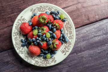 Fresh berries mix. Strawberry, blueberry and gooseberries on wooden table. Top view