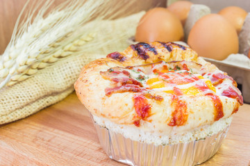 Baked sandwich with egg, cheese and ham. Hot breakfast. Bun with liquid egg, ham and melted cheese on natural wooden background.
