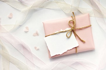 Handmade simple gift wrap, craft soft delicate pink paper, ribbons, empty note, twine bow. Soft romantic invitation top view background. 