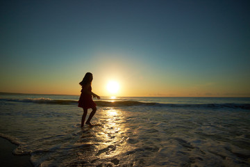 Fototapeta na wymiar girl playing on the beach at sunset