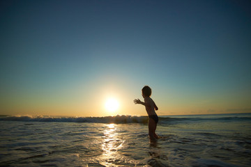 Fototapeta na wymiar boy playing on the beach at sunset