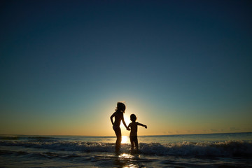 Fototapeta premium boy and girl on the sea at sunset