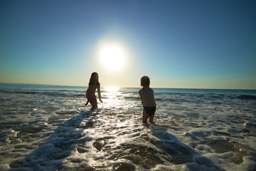 boy and girl on the sea at sunset