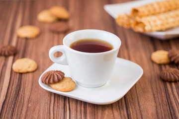 cup of tea on a saucer with cookies on the wooden table