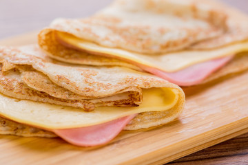 pancakes with ham and cheese on a wooden board