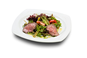 warm salad with beef slices of pickled cucumbers and capers on a white plate and a white background