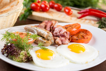 Breakfast. Scrambled eggs with Bavarian sausages and bacon. On a white plate