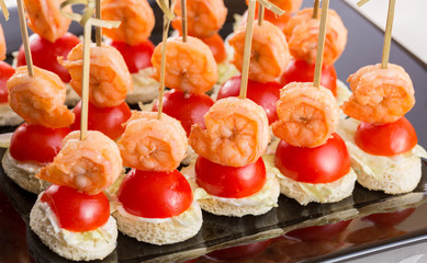 Canape of shrimp tomato bread. On a black plate