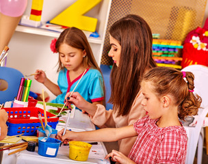 Children with teacher woman painting on paper at table in primary school. Teacher learn teacher.