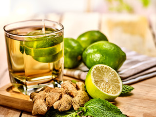 Healthy detox drink with ginger . On wooden boards glass with green tea and mint. Mint ginger drink number three hundred thirty five with half lime .