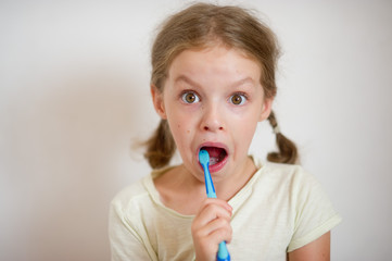 Cute girlie with pigtails diligently brushing his teeth.