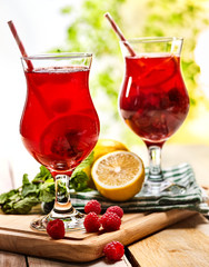 Wooden boards are ice cold beverage two glasses with red berries lemon cocktail . Alcohol cocktail number three hundred fourty three with leaf mint.