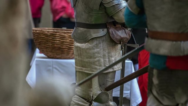 Knights in armour are standing still. They also have their swords behing their waist. Close-up shot.
