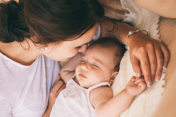 Beautiful young mom near sleeping 3 months baby.