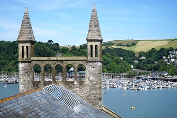 Double turrets on the roof of a historic church in the coastal town of Dartmouth, Devon, overlooking a large marina in the estuary of the River Dart.