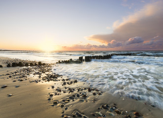 dynamic landscape of sea, the waves breaking on the breakwater, sunset on the sea beach
