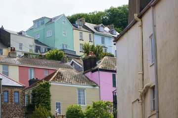 Fototapeta na wymiar Colourful exterior paint brightens a group of houses on a hillside in the British coastal town of Dartmouth, Devon. 