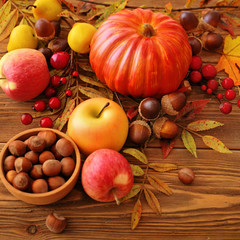 autumn fruits, flowers and leaves on wooden background