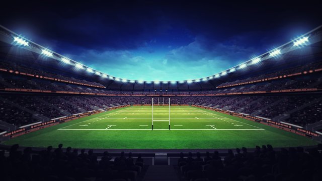 illuminated rugby stadium with spectators and green grass