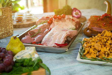 Raw meat and small tomatoes. Plate with yellow mushrooms. Dish requires lots of ingredients. Prepare meal at special recipe.