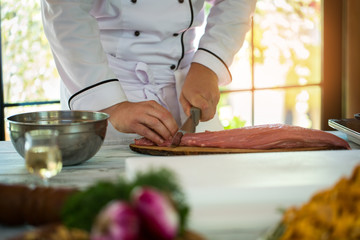 Man with knife cuts meat. Sirloin on wooden board. Chef is busy all day. Must put more effort.