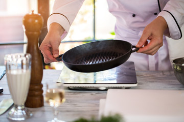 Man's hands hold frying pan. Pan of black color. New teflon kitchenware. Thin layer of oil.