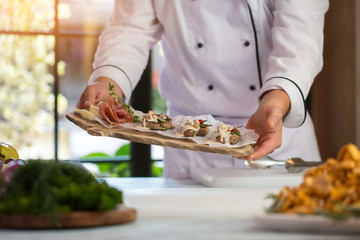 Hands hold board with meat. Bacon and green herb. Beef medallions with roquefort sauce. Enjoy your dinner.