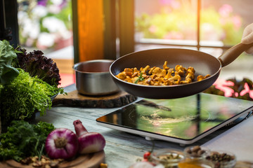 Frying pan with yellow mushrooms. Lettuce of green color. Very delicious fried chanterelles. Cook food from natural ingredients.