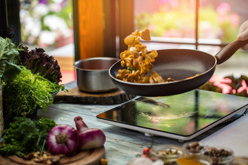Black pan with mushrooms. Purple onion and greenery. Recipe of fried chanterelles. Cook uses only natural products.