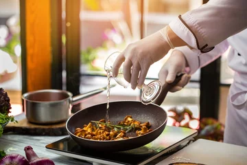 Photo sur Plexiglas Plats de repas Liquid pours onto mushrooms. Hand holding glass over pan. Chanterelles fried in wine. Chef tries new recipe.