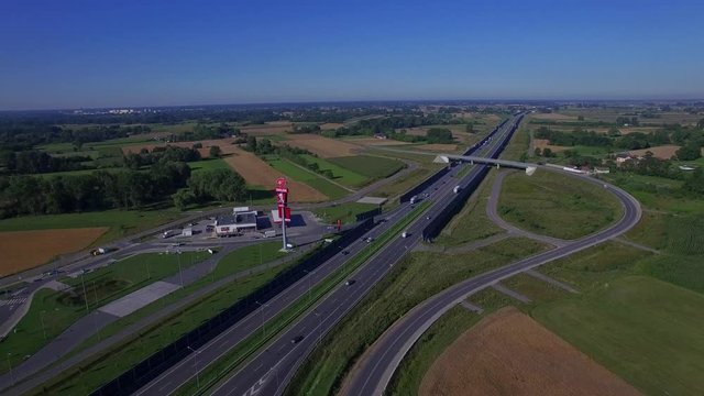 Highway countryside with cars traffic and gas station aerial 4K HD top view from above. Fly over road vehicles cars lorry trucks moving divided highway overpass bridge sunny day in Poland East Europe