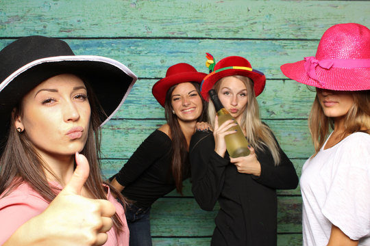 4 Mädchen mit Damenhüten und Sekt vor einer Fotobox - Mädchen zeigen Daumen hoch 