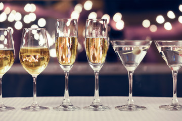 Assortment of wine, champagne, and martini alcoholic drinks lined up on a bar table. 