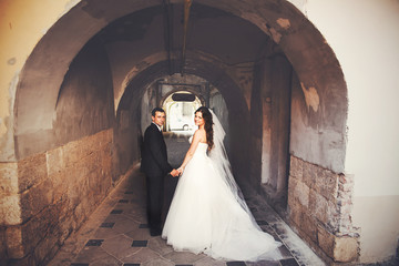 Bride and groom look over their shoulders walking in the alley