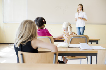 Female teacher teaching class in front of whiteboard