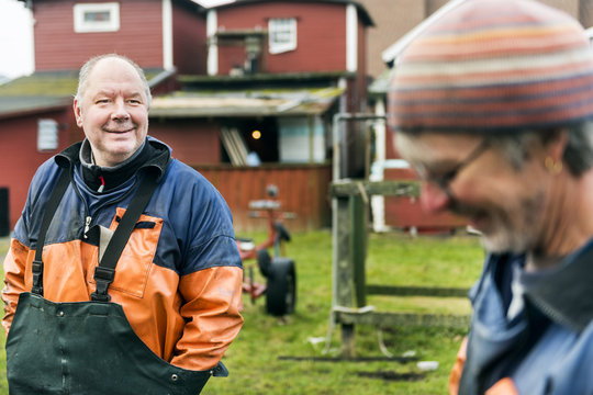 Mature fisherman looking at male colleague outdoors