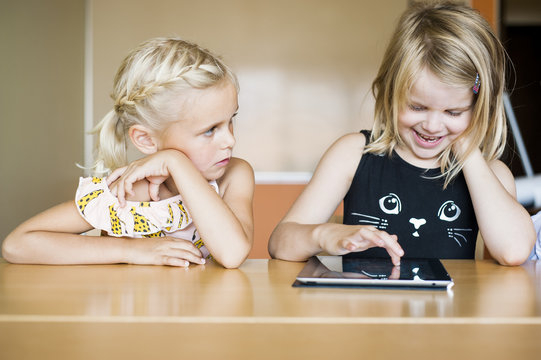 Two girls using digital tablet at table