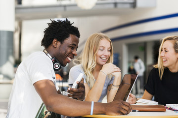 Happy multiethnic friends studying at table in cafe