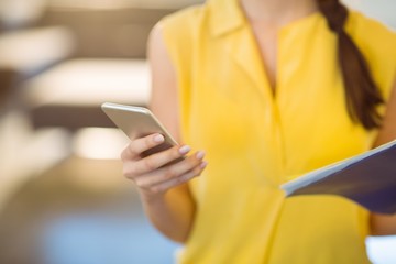 Mid-section of female business executive using mobile phone