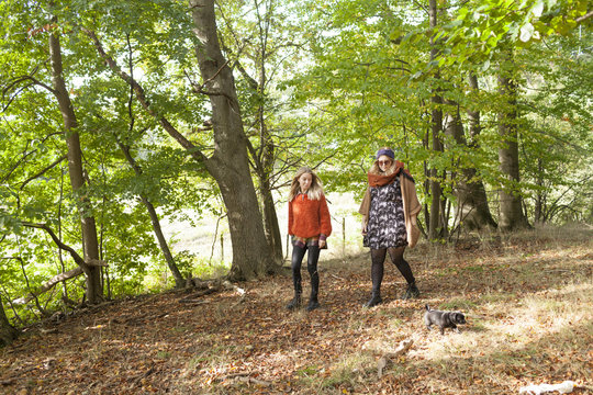 Full length of young women with puppy walking in forest