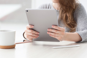 woman sitting in summer cafe drinks tea holding tablet computer