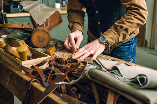 Midsection of man working at workbench in bag factory