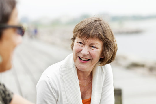 Happy Senior Woman Talking With Female Friend At Seashore