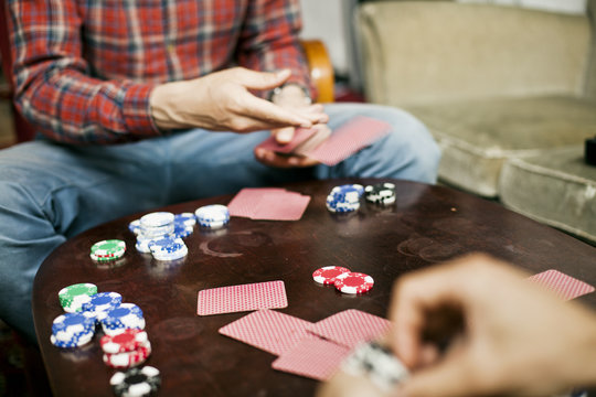 Cropped image of men playing cards at home