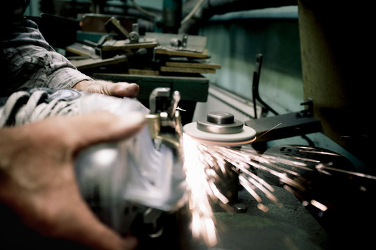 Cropped image of worker's hands sharpens the blades on skate in workshop