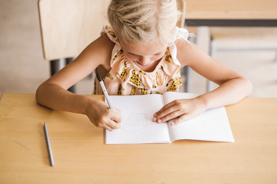 Girl writing in book at desk in classroom