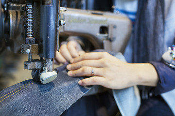 Cropped of male fashion designer using sewing machine in jeans factory