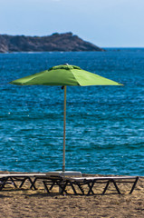 Sandy beach with one green sunshade at morning in Sithonia, Greece