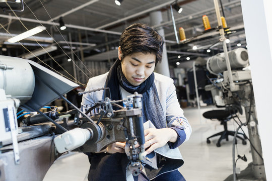 Male fashion designer using sewing machine in jeans factory